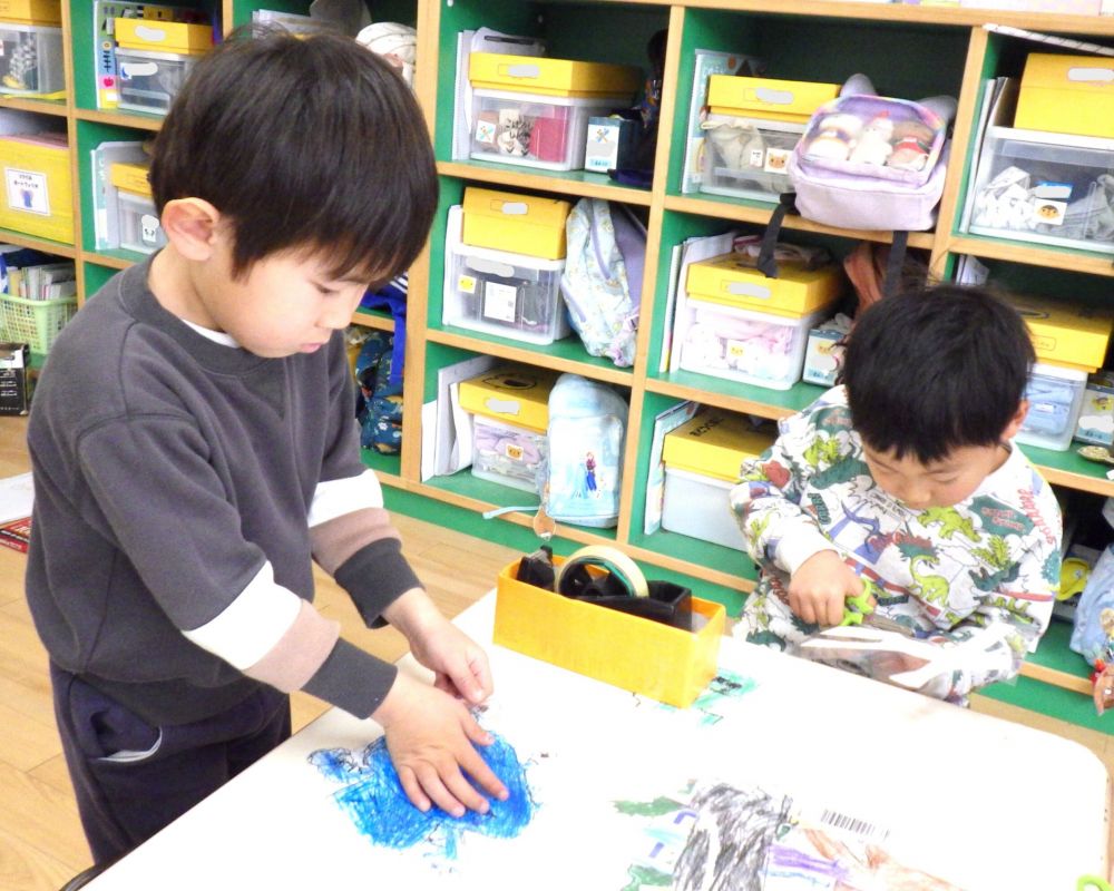 そしてついに絵が完成！
何度も遊べるようにラミネートで頑丈にしたあとは
お客さんや自分たちがけがをしないよう角を丸く切っていきます
日頃の廃材製作の経験を活かし、敵を自立させるためには箱に絵を貼ることに！
自分の敵の大きさを確認し・・・
「この箱がちょうどいい！」
「箱と箱を合体させよ～」
「この大きいペットボトルいいね」
剥がれにくい布ガムテープを選び、テープが表から見えないように工夫しながら敵を完成させました★

