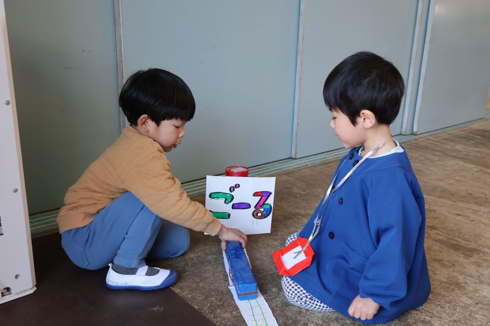 I君が作った青い新幹線【かがやき】を気に入ってくれた様子のK君。
そっと側に行って
「ここがゴールだよ」
と教えてあげるI君。
自分より小さな友達に優しく声を掛けてあげることができる素敵なお兄さんになったね。

約１か月かけて進めてきた協同遊び。
少しずつですが、みんなの前で考えを発表することが苦手だった子も、
グループで話をする機会が増え、
少人数での話し合いを経験することで
自分の意見を言葉で伝えることだ出来るようになってきました。
日々の遊びや生活の中で、
自分の思いを伝え、相手の話しを聞き、
思いに気付くことが出来る力を身に付けていけたらと思います。

