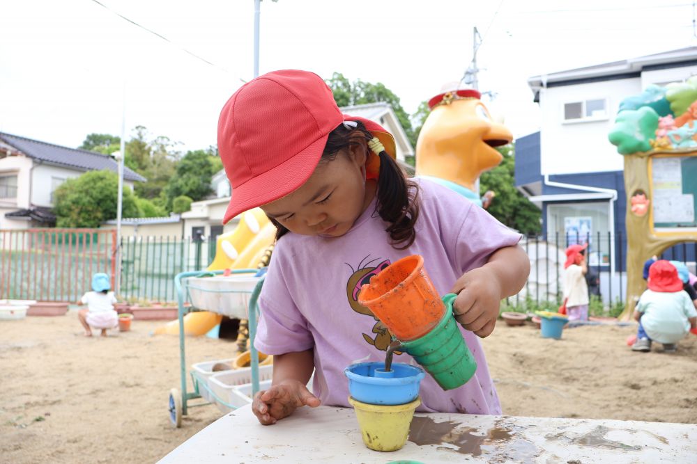 昨日の雨で、水たまりも出来て楽しい泥遊びが広がっていた園庭。
泥団子を作ったり、水しぶきを上げて鬼ごっこをしたりして楽しんでいたゾウ組さん。

Rちゃんは泥んこを使ってコーヒー屋さんごっこ！
Rちゃん「なににしますか？コーヒーどうぞ♡」

砂場のおもちゃを組み合わせて、まるで本物のドリップコーヒーみたい✨