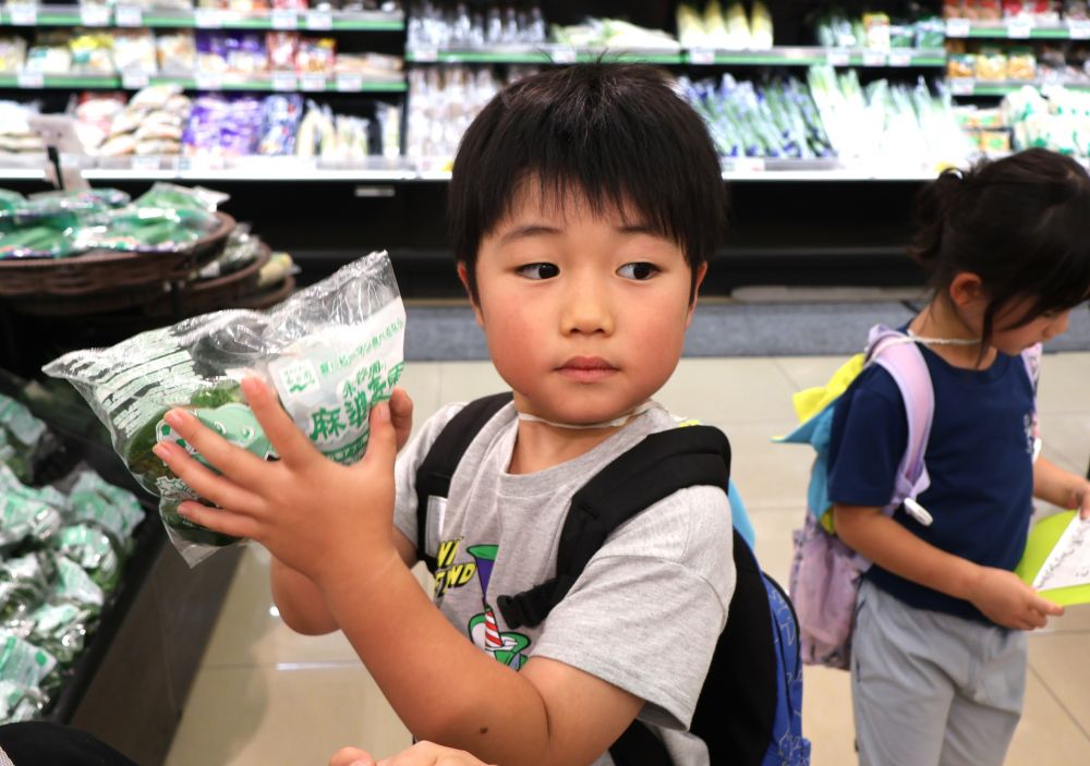 「次はなにー？」
「ピーマンじゃけえ野菜売り場よね」

みんなで野菜売り場でピーマンを探します。
「あったよ！！」

少し高めのピーマンを見つけたRちゃんですが、、、
店員さんに　「あっちにもピーマンあるよ」
と、声をかけていただき別の場所でちょうどいいピーマンを発見✨

「これにしよう！！」


